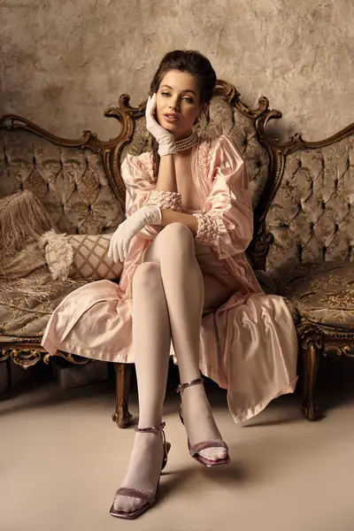 A beautiful young woman dressed as a nymph relaxes on an ornate vintage couch, exuding charm. — Stock Photo