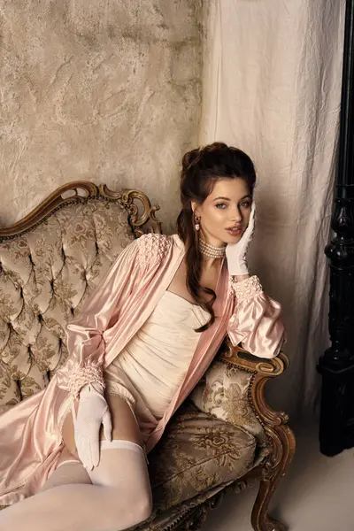A beautiful young woman dressed in vintage fantasy attire lounges gracefully in an elegant setting. — Stock Photo