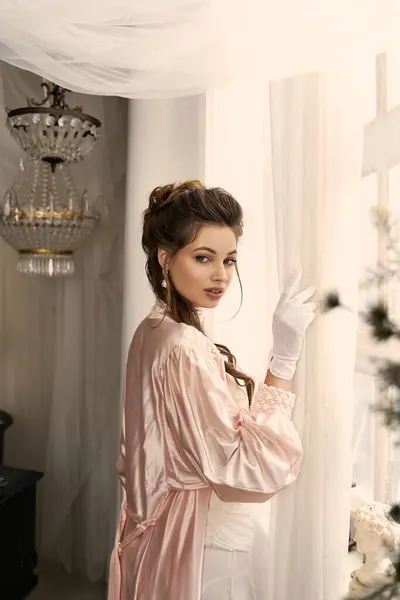 A young woman dressed in vintage attire gazes out the window, lost in enchanting thoughts. — Stock Photo