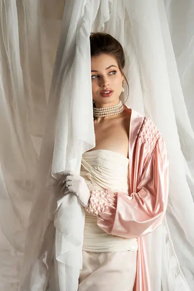 A lovely young woman in vintage attire poses gracefully with flowing fabric, exuding charm. — Stock Photo