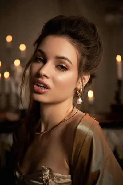 A young woman with ethereal beauty embodies a mystical vampire, surrounded by flickering candles. — Stock Photo