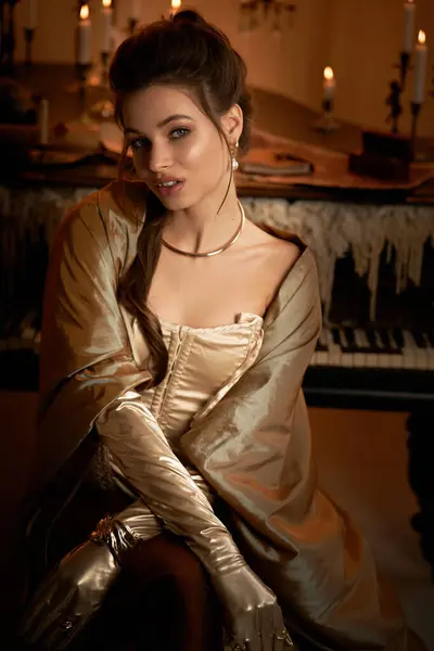 A young woman draped in glamorous fabric sits gracefully, surrounded by candles in a mystical room. — Stock Photo