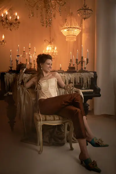 A young, beautiful vampire reclines gracefully in a lavish room filled with candles and chandeliers. — Stock Photo