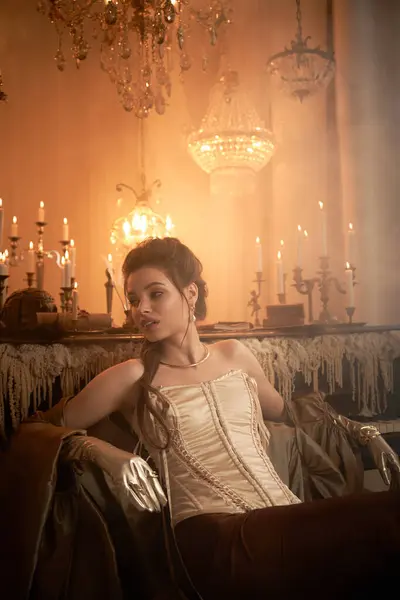 A young woman with captivating beauty exudes an alluring mystery in a luxurious, dimly lit setting. — Stock Photo