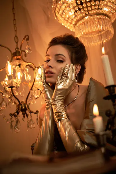 Eine junge Frau verkörpert eine Vampirfantasie, trägt goldene Handschuhe im warmen Kerzenschein. — Stockfoto