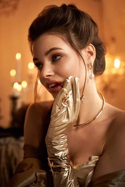 A young woman in golden gloves ponders in a candlelit, mystical room. — Stock Photo