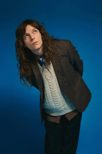 A stylish young man with long hair confidently shows off his unique fashion flair. — Stock Photo