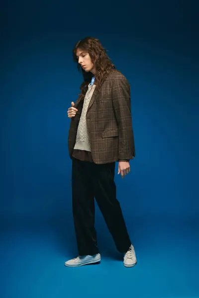 Stylish young man stands confidently in a chic outfit against a vivid blue background. — Stock Photo