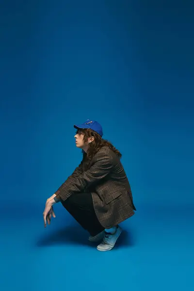 Fashionable young man crouches confidently, showcasing a chic style contrasted by bold colors. — Stock Photo