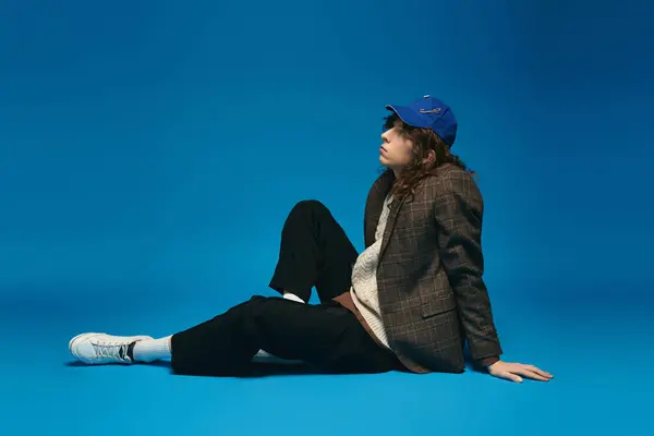 Dressed in chic attire, a young man sits confidently while exuding a trendy vibe in a bold setting. — Stock Photo