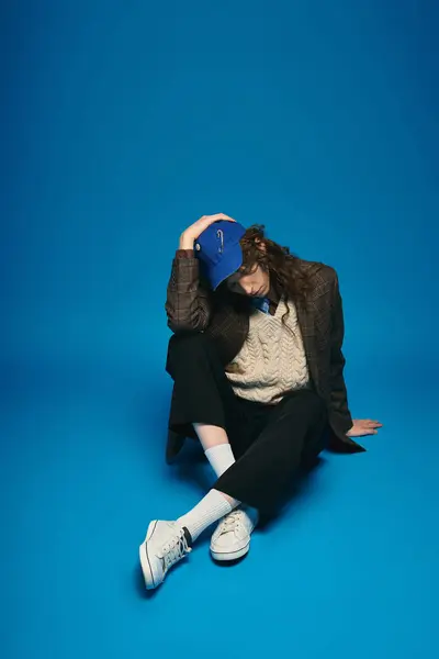 A stylish young man sits confidently in a vibrant blue setting. — Stock Photo