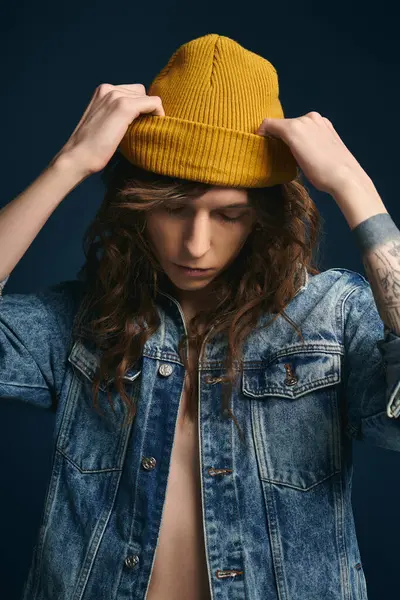 Young man in trendy denim jacket and yellow beanie creates a chic fashion statement with confidence. — Stock Photo