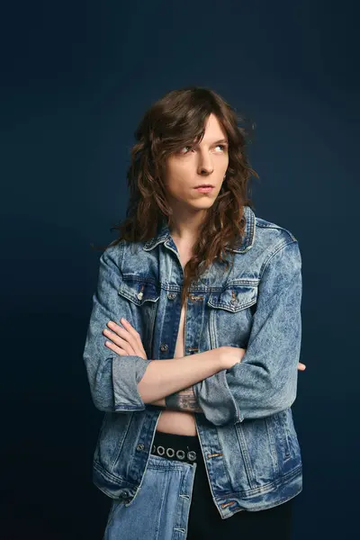 A young man confidently poses in stylish denim against a dark backdrop. — Stock Photo