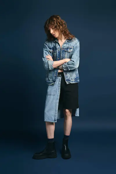 Confident young man in denim stands stylishly against a dark backdrop, showcasing modern fashion. — Stock Photo
