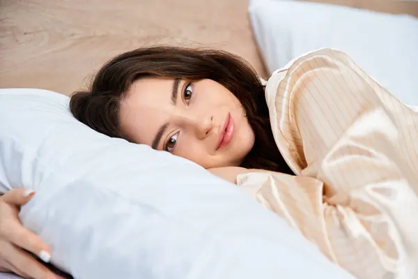 A young woman relaxes on a bed, radiating calmness and comfort in soft morning light. — Stock Photo