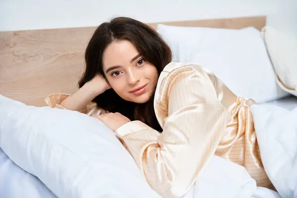 A beautiful young woman lounges on her bed, exuding serenity and elegance in the warm light. — Stock Photo