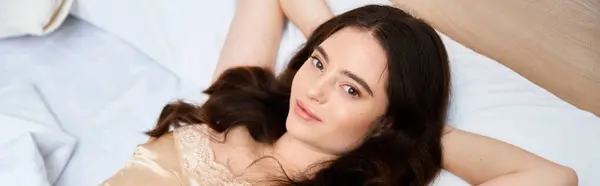 A beautiful young woman lies on a soft bed, enjoying a moment of peace and tranquility. — Stock Photo