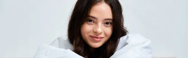 A beautiful young woman smiles warmly, wrapped in soft fabric, radiating joy and tranquility. — Stock Photo