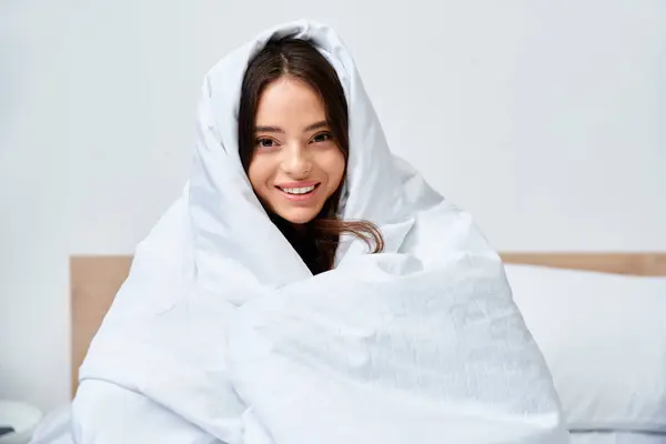 A young woman smiles happily in her cozy, minimalist bedroom. — Stock Photo