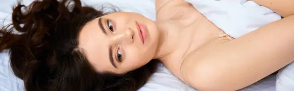 Gentle light illuminates a young, beautiful woman as she relaxes comfortably on a cozy bed. — Stock Photo
