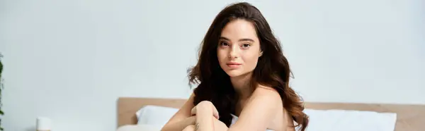 A charming young woman sits peacefully on a bed, radiating tranquility. — Stock Photo