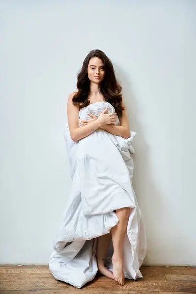 A young woman stands elegantly wrapped in soft fabric, exuding confidence and calmness. — Stock Photo