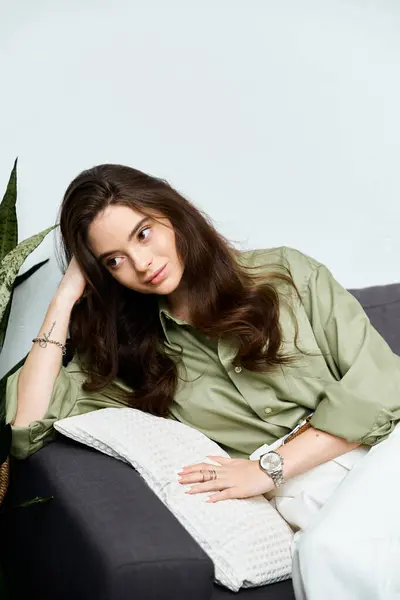 In a calm room, a stylish young woman with long hair relaxes on a couch. — Stock Photo