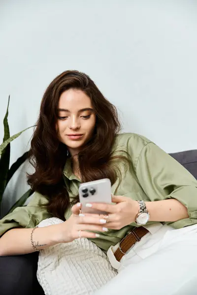 A beautiful young woman is lost in thought, interacting with her smartphone in a cozy setting. — Stock Photo