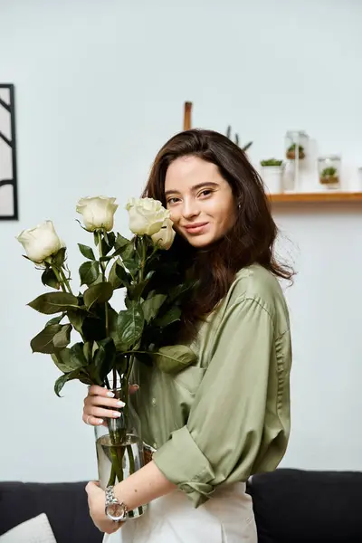 A beautiful young woman holds a bouquet of white roses, radiating joy in a modern home interior. — Stock Photo