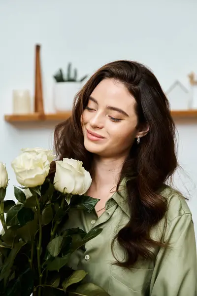 Uma bela jovem admira suavemente um buquê de rosas brancas em um ambiente tranquilo interior. — Fotografia de Stock