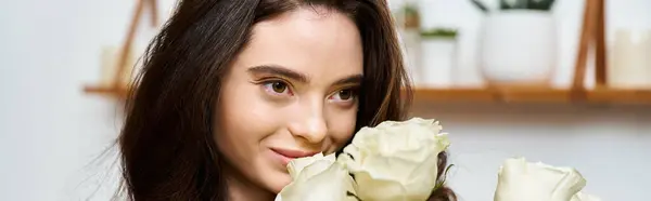 A beautiful young woman smiles while embracing white roses in a charming indoor setting. — Stock Photo