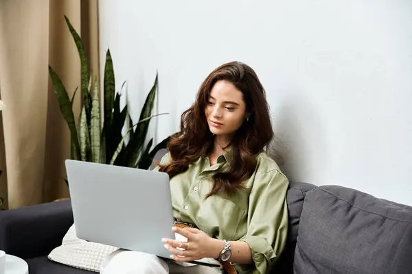 Una giovane donna con i capelli lunghi lavora sul suo computer portatile, circondata da piante d'appartamento accoglienti. — Foto stock