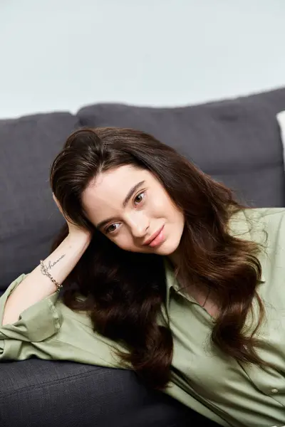 A young woman relaxes on a soft, vibrant green couch, radiating charm and serenity. — Stock Photo