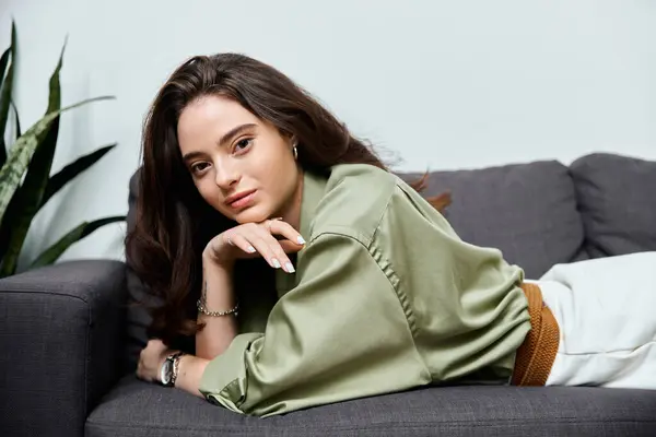 Uma bela jovem mulher salta graciosamente em um sofá moderno, exalando charme e confiança. — Fotografia de Stock