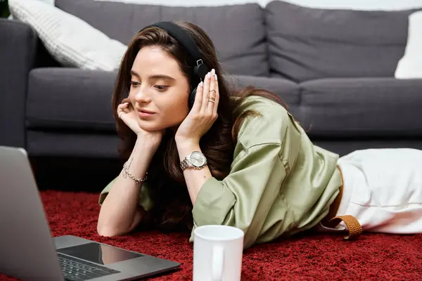 A young woman lounges comfortably on a soft rug, lost in music with her headphones on. — Stock Photo