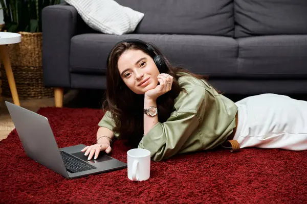 Relaxing on a soft rug, a young woman engages with her laptop, immersed in her work. — Stock Photo