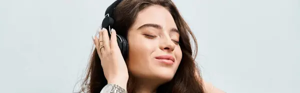 Young woman smiles blissfully while listening to her favorite songs and enjoying the moment. — Stock Photo