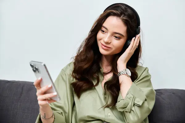 Une belle jeune femme se détend sur un canapé, immergée dans sa musique préférée à l'aide d'écouteurs. — Photo de stock