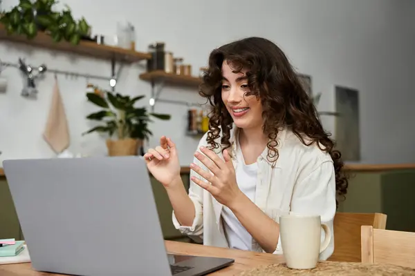 Cheerful woman chats animatedly from her cozy home space while sipping coffee in the morning light. — Stock Photo