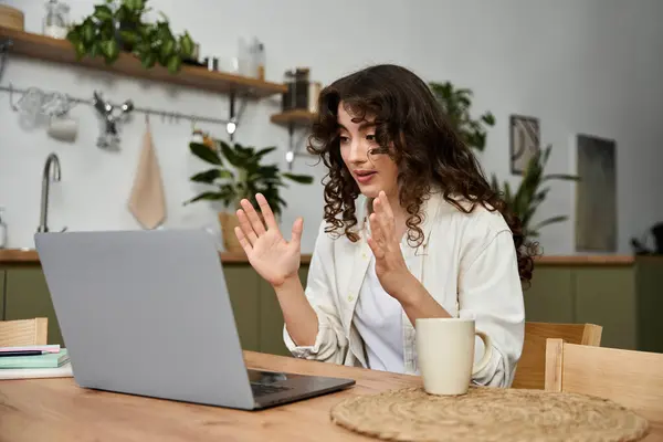 A young woman sips from a mug while using her laptop, creating a cozy vibe. — Stock Photo