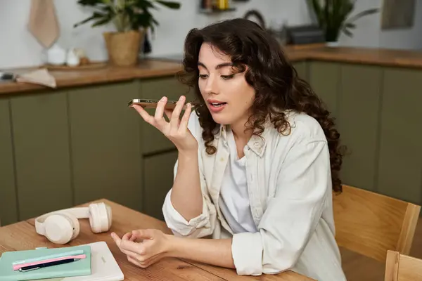 A young woman enjoys a lively voice call in her stylish home kitchen with casual decor. — Stock Photo