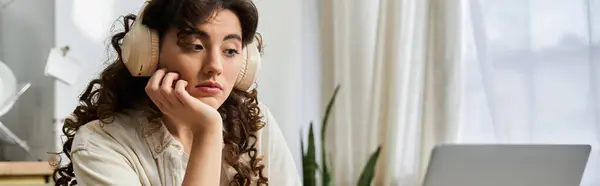 A beautiful young woman with curly hair listens thoughtfully with headphones in a peaceful space. — Stock Photo