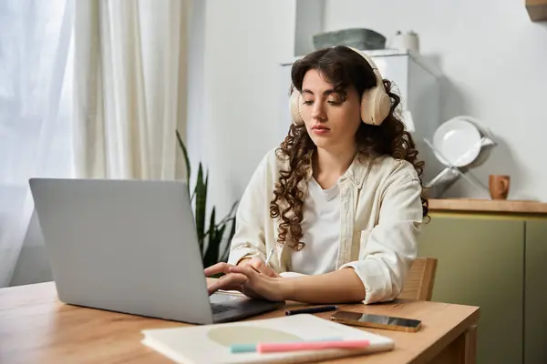 A young woman in headphones types on her laptop, focused on her home tasks. — Stock Photo