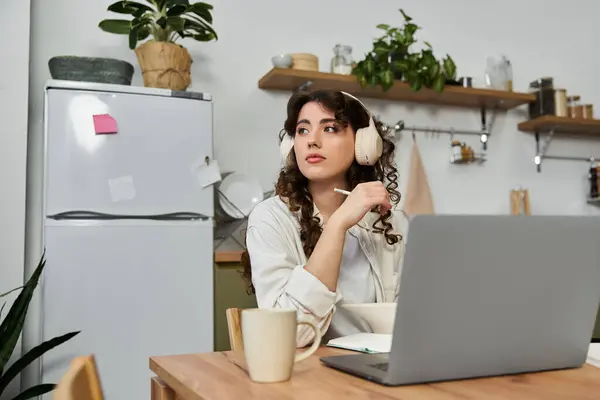 A young woman relaxes at home, lost in thought with cozy headphones on. — Stock Photo
