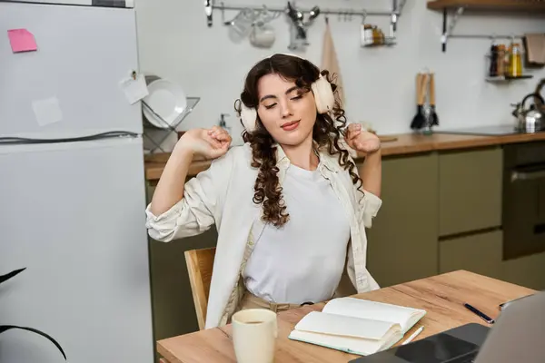 Young woman in a cozy home stretches and enjoys her favorite tunes over a warm beverage. — Stock Photo