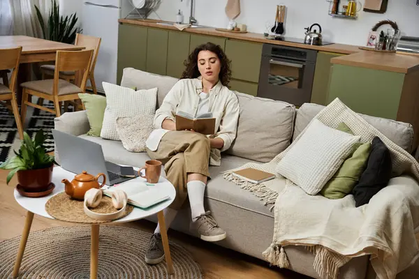 Junge Frau genießt einen ruhigen Moment beim Lesen zu Hause, umgeben von bequemer Dekoration. — Stockfoto