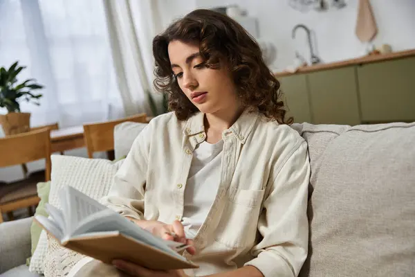 Relaxed atmosphere fills the room as a beautiful woman reads thoughtfully on the couch. — Stock Photo
