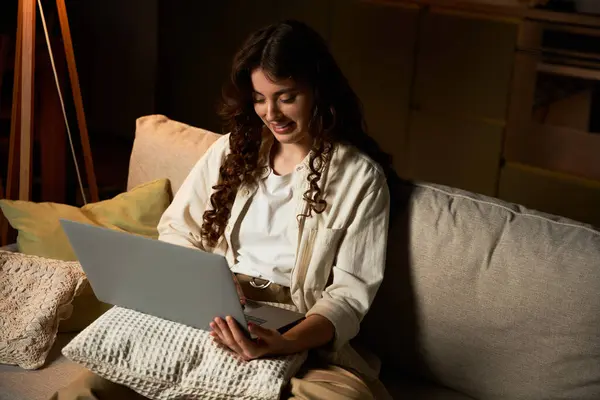 A beautiful young woman enjoys her evening at home, focused on her laptop while sitting comfortably. — Stock Photo