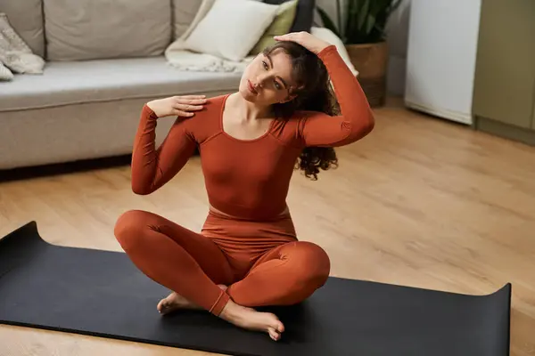 Frau in kuscheliger Kleidung dehnt sich auf einer Yogamatte und genießt einen Moment der Ruhe zu Hause. — Stockfoto