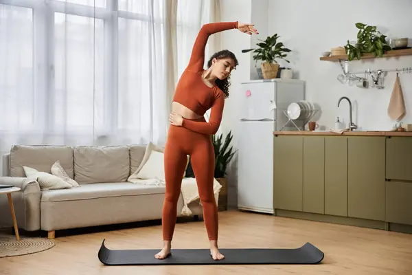 Una giovane donna si allunga con grazia nella luce calda, godendo lo yoga nella sua bella casa. — Foto stock